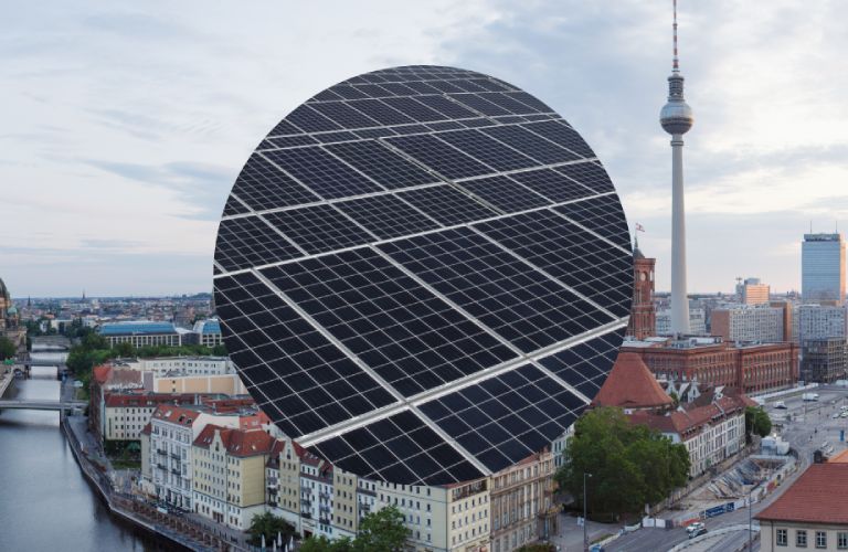 Blick über die Skyline von Berlin mit Sicht auf die Spree und den Fernsehturm. Im Vordergrund eine Nahaufnahme einer Photovoltaikanlage.