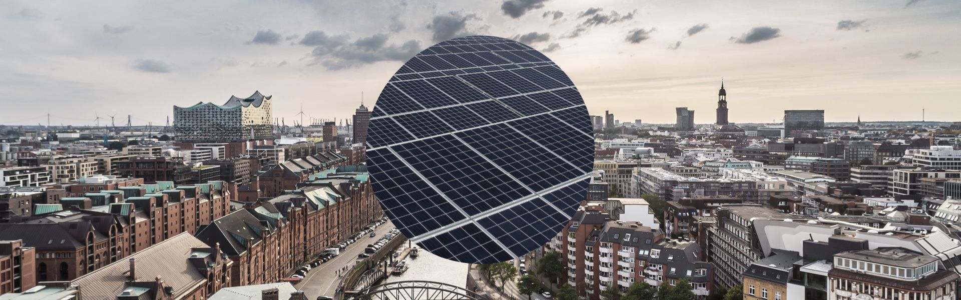 Blick über die Skyline von Hamburg mit Sicht auf die Speicherstadt. Im Hintergrund sind die Michaeliskirche und die Elbphilharmonie zu sehen. Im Vordergrund eine Nahaufnahme einer Photovoltaikanlage.