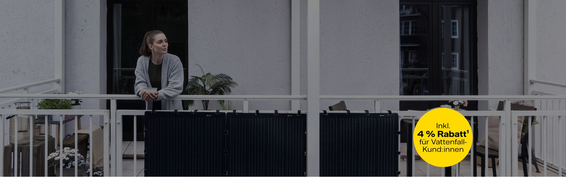 Aktion: 4 % Rabatt für Vattenfall-Kund:innen. Eine Frau lehnt entspannt an einem Balkon, an dem schwarze Solarpaneele befestigt sind.