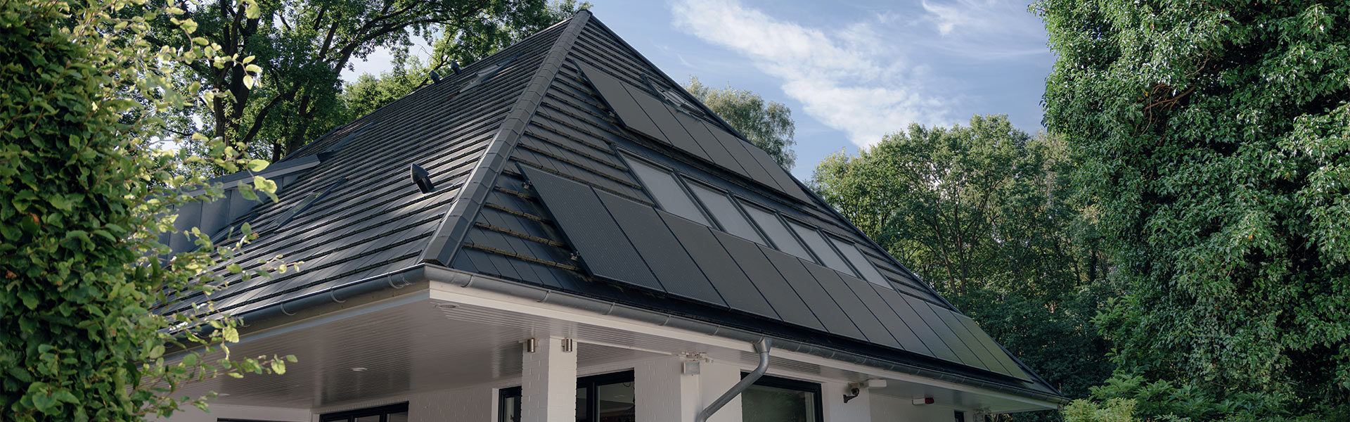 Solarpaneele auf einem Einfamilienhaus umgeben von grünen Bäumen.