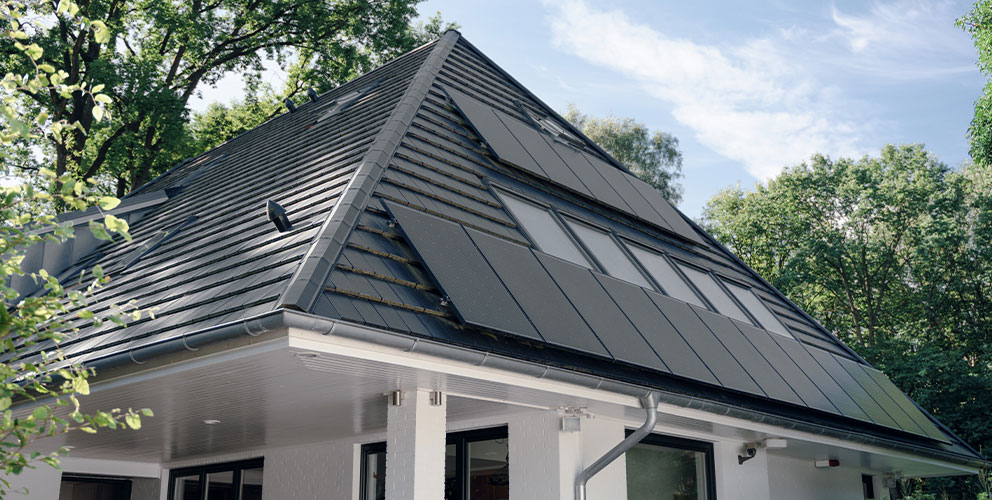 Solarpaneele auf einem Einfamilienhaus umgeben von grünen Bäumen.