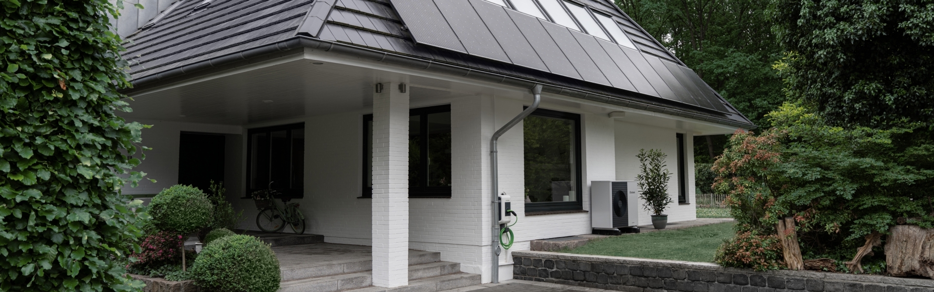 Eine Photovoltaikanlage auf einem Einfamilienhaus, das von Bäumen umgeben ist.