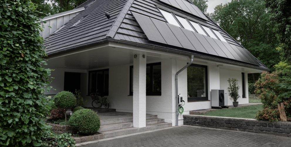 Eine Photovoltaikanlage auf einem Einfamilienhaus, das von Bäumen umgeben ist.