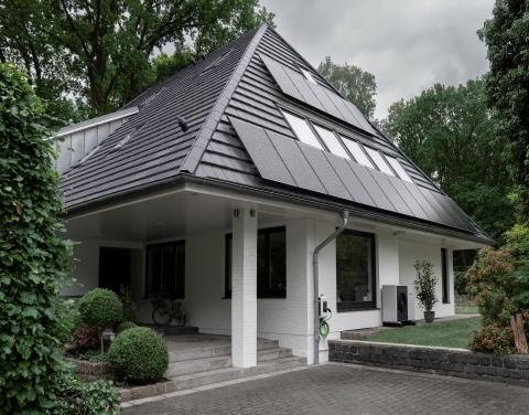 Eine Photovoltaikanlage auf einem Einfamilienhaus, das von Bäumen umgeben ist.