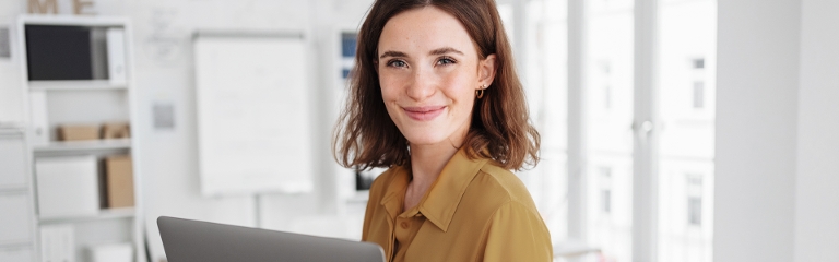 Frau am Laptop lächelt in die Kamera