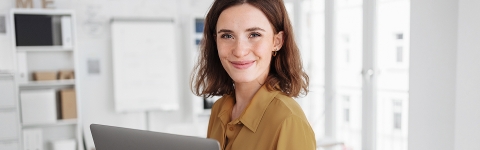 Frau am Laptop lächelt in die Kamera