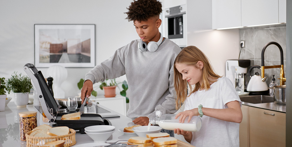 2 Jugendliche bereiten Essen in der Küche zu.