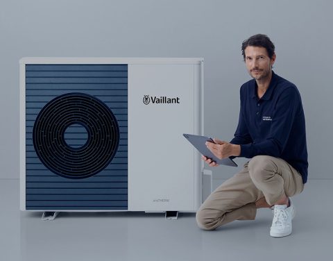 Mann sitzt vor einer Wärmepumpe