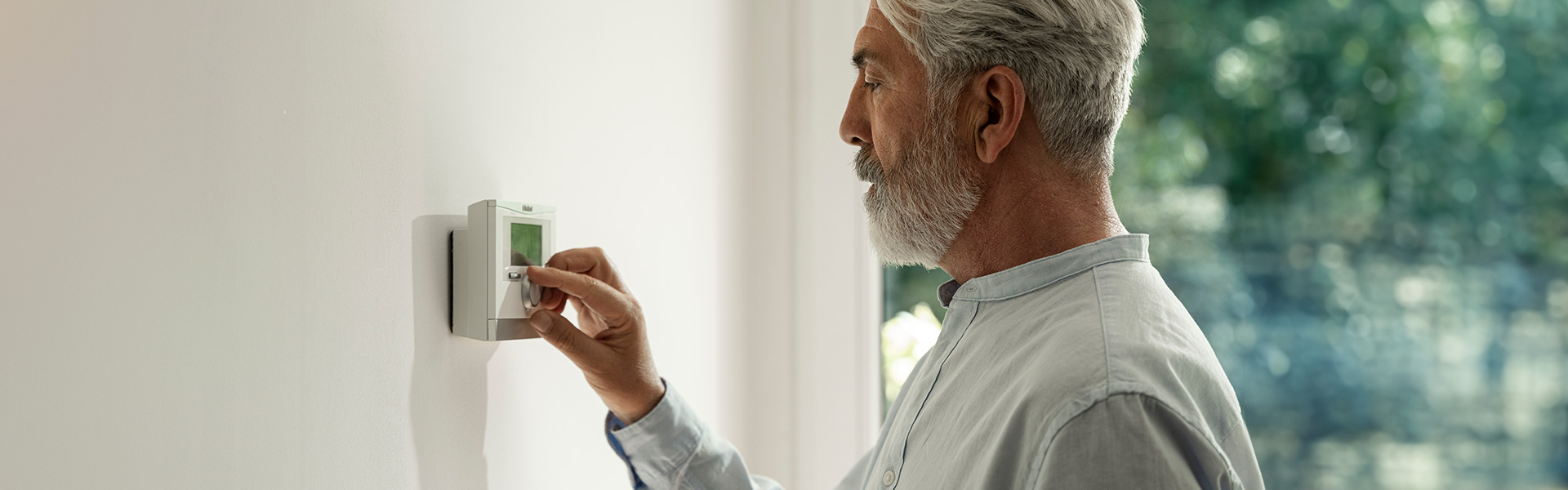 Ein Mann bedient eine an der Wand angebrachte moderne Steuerung für die Raumtemperatur.
