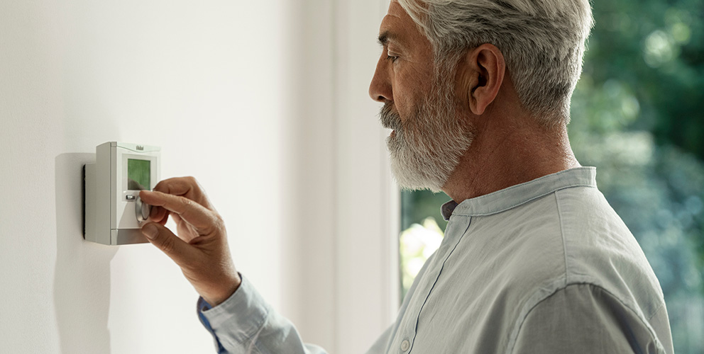 Ein Mann bedient eine an der Wand angebrachte moderne Steuerung für die Raumtemperatur.