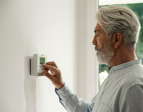 Ein Mann bedient eine an der Wand angebrachte moderne Steuerung für die Raumtemperatur.