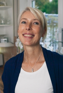 Mann und Frau stehen in einer modernen und hellen Küche. Beide blicken freudig in die Kamera.