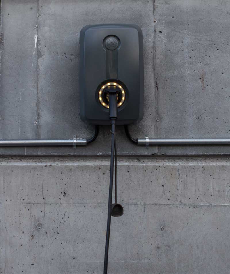 schwarze Wallbox hängt an einer Betonwand